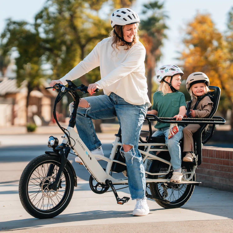Parent riding a Lectric cargo e-bike with two children